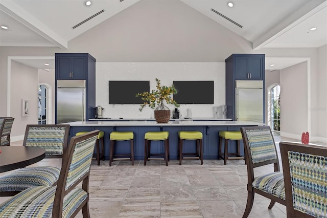 kitchen with built in fridge, lofted ceiling, and blue cabinets