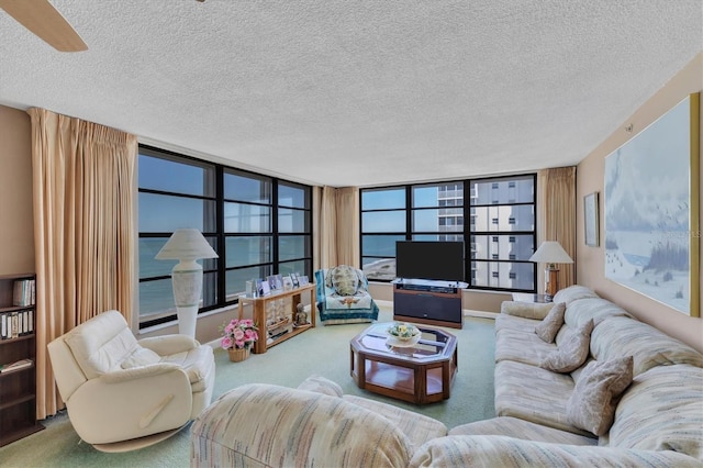 carpeted living room with ceiling fan, floor to ceiling windows, and a textured ceiling