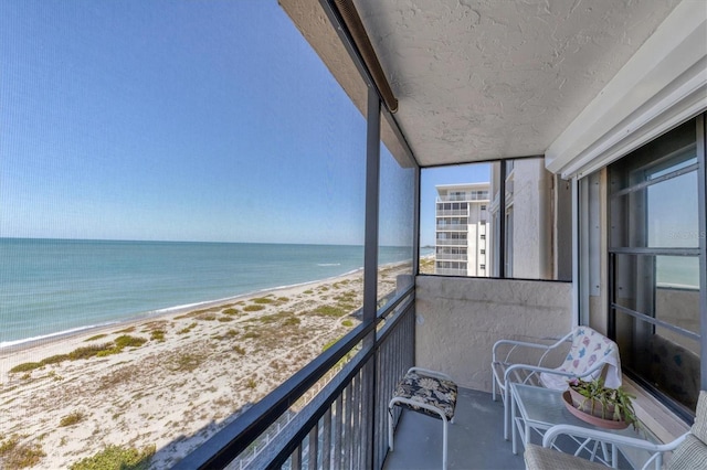 balcony featuring a view of the beach and a water view