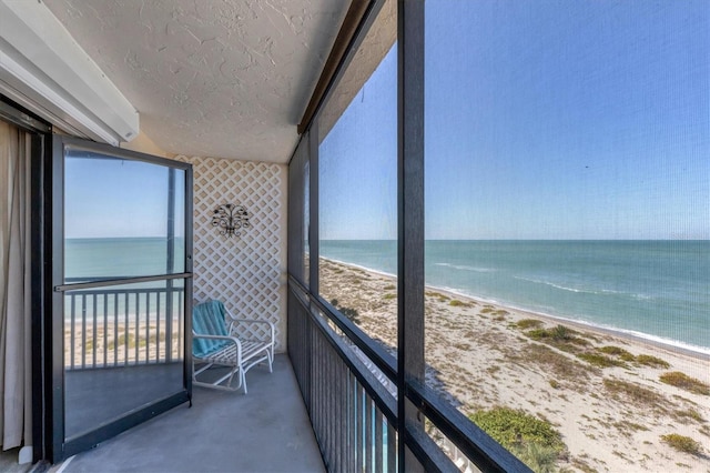 unfurnished sunroom with a view of the beach and a water view