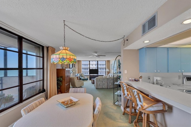 carpeted dining space featuring ceiling fan and a textured ceiling