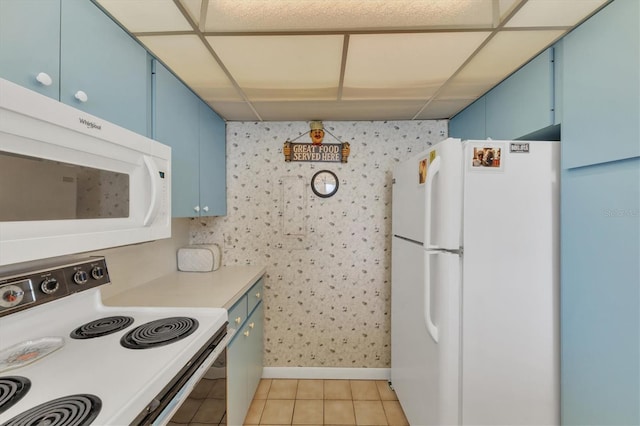 kitchen with a paneled ceiling, light tile patterned flooring, white appliances, and blue cabinetry