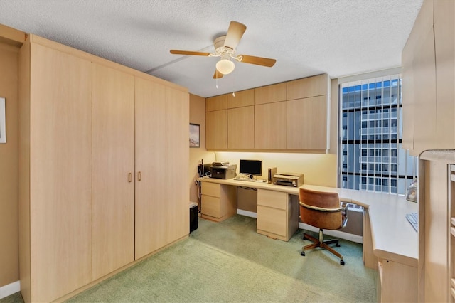 office space featuring light colored carpet, built in desk, and a textured ceiling