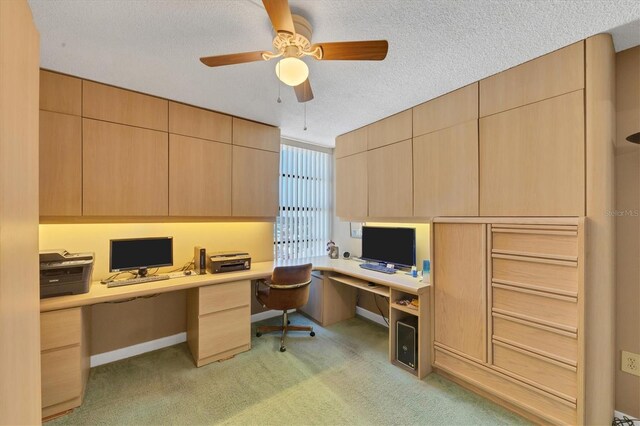 carpeted office featuring ceiling fan, built in desk, and a textured ceiling