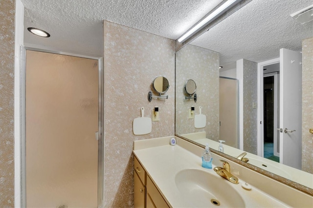 bathroom featuring vanity, a textured ceiling, and an enclosed shower