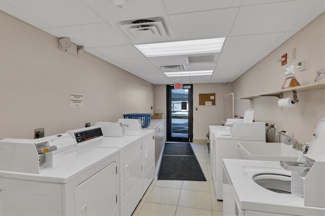 washroom with washer and clothes dryer, light tile patterned floors, and sink