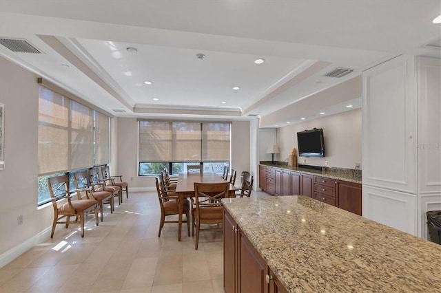 kitchen featuring a tray ceiling, light stone counters, and light tile patterned floors