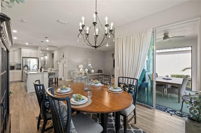 dining room with light wood-type flooring and ceiling fan with notable chandelier