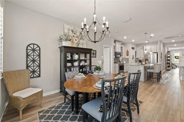 dining space with light wood-type flooring, visible vents, a notable chandelier, and baseboards