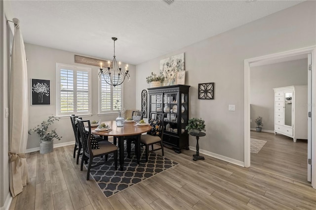 dining space featuring hardwood / wood-style flooring, a textured ceiling, and a notable chandelier