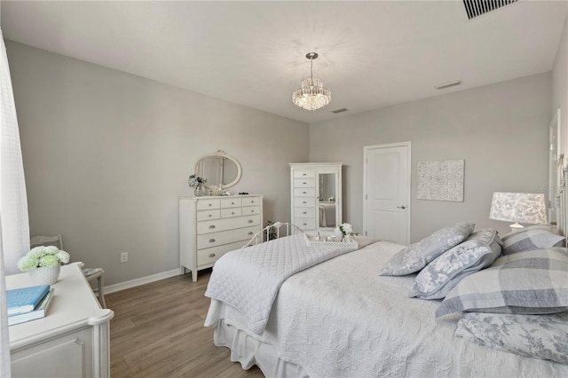 bedroom with light wood-type flooring, visible vents, a notable chandelier, and baseboards