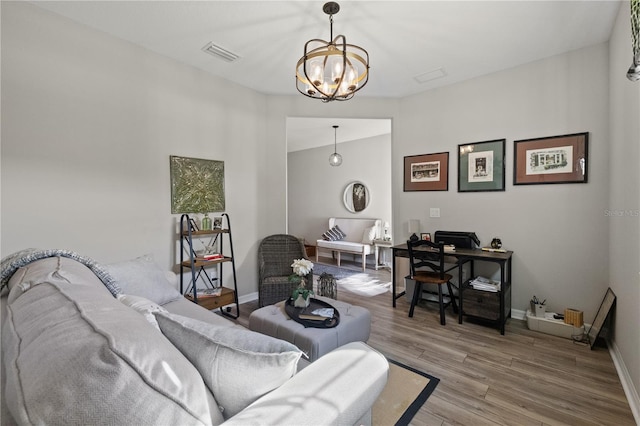 living room with a chandelier, wood finished floors, visible vents, and baseboards