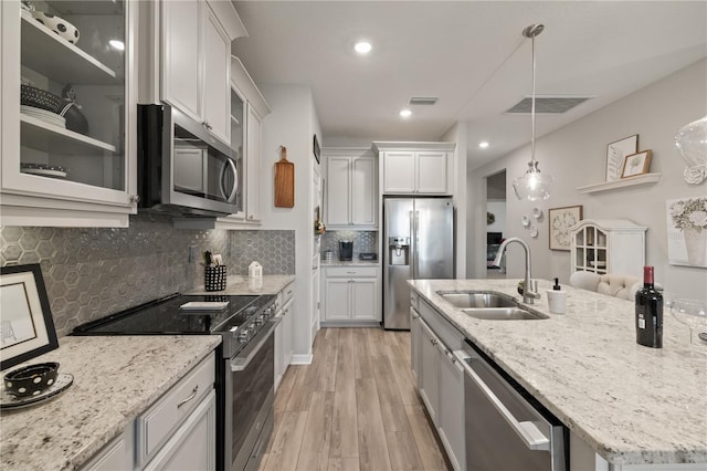 kitchen with stainless steel appliances, glass insert cabinets, a sink, and white cabinetry