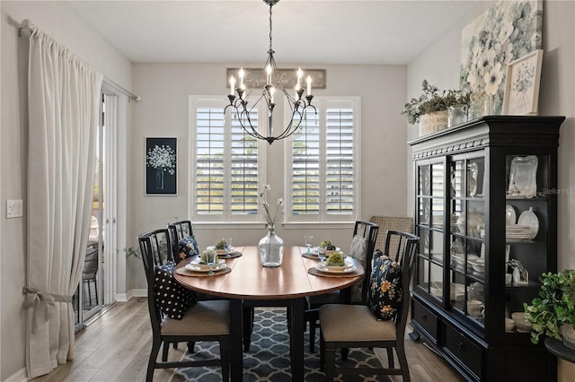 dining space with a notable chandelier, baseboards, and wood finished floors