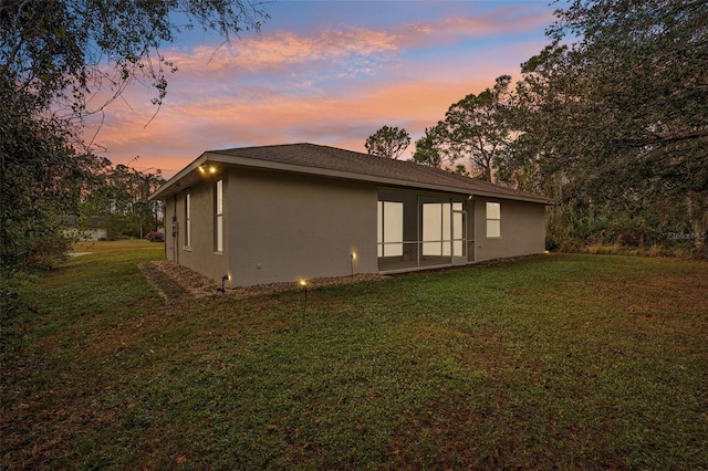 view of side of home with stucco siding and a yard