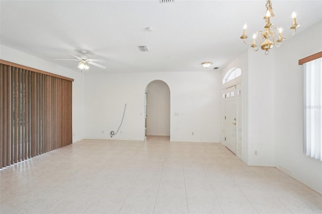 empty room featuring arched walkways, ceiling fan with notable chandelier, and visible vents