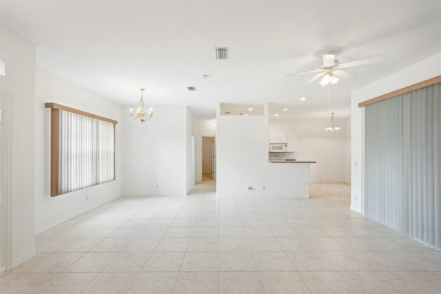 empty room with light tile patterned floors, visible vents, and ceiling fan with notable chandelier