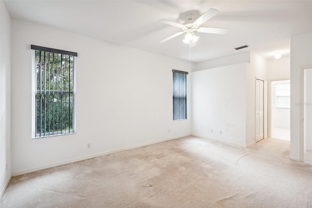 unfurnished room featuring baseboards, a ceiling fan, visible vents, and light colored carpet