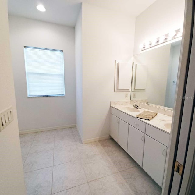 bathroom featuring double vanity, baseboards, a sink, and tile patterned floors