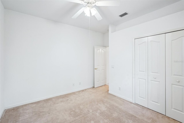 unfurnished bedroom with light carpet, baseboards, visible vents, a ceiling fan, and a closet