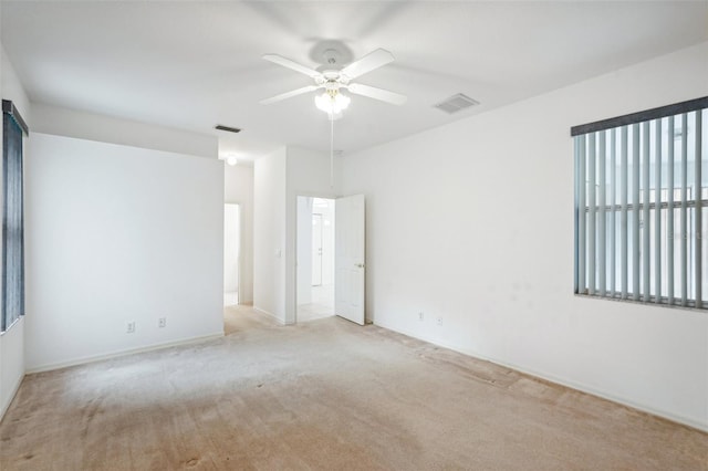 unfurnished room with a ceiling fan, light colored carpet, and visible vents