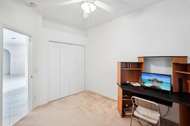 home office with arched walkways, ceiling fan, baseboards, and light colored carpet