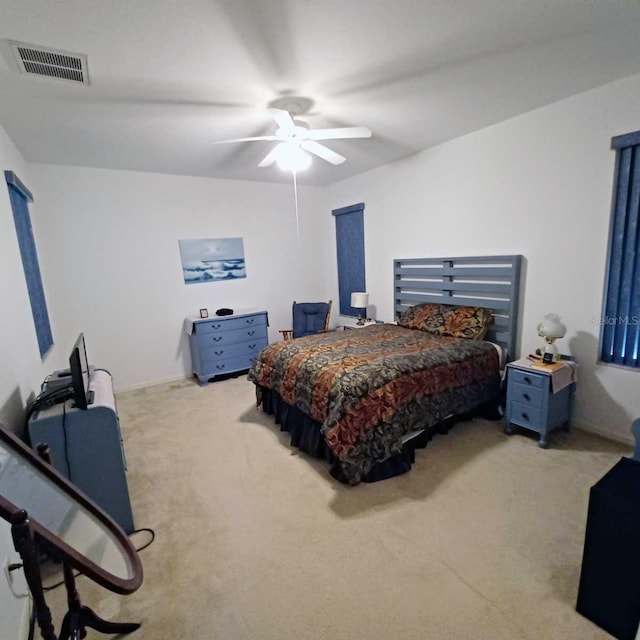 bedroom with ceiling fan, visible vents, baseboards, and light colored carpet