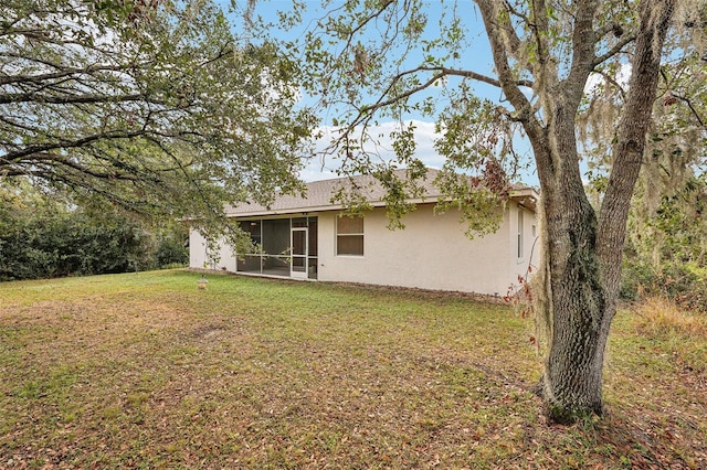 back of house with a sunroom, a lawn, and stucco siding