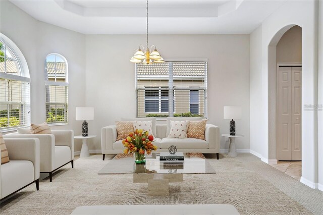 134 Savona Way N, Venice, FL 34275 - living room with arched walkways, a chandelier, a tray ceiling, and carpet flooring