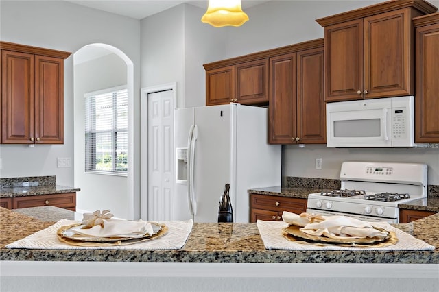 kitchen with dark stone countertops and white appliances