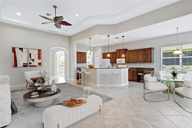 134 Savona Way N, Venice, FL 34275 - living area featuring a ceiling fan, arched walkways, recessed lighting, a tray ceiling, and light tile patterned floors