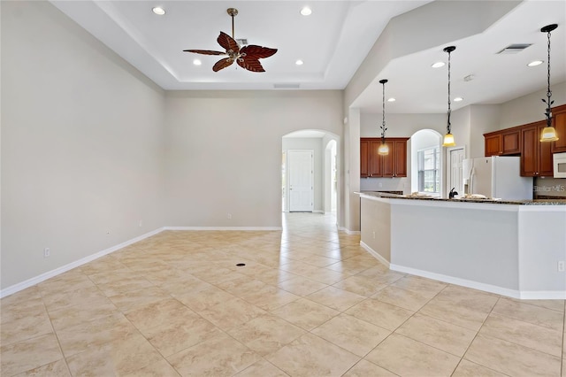 kitchen with light stone countertops, ceiling fan, decorative light fixtures, and white appliances