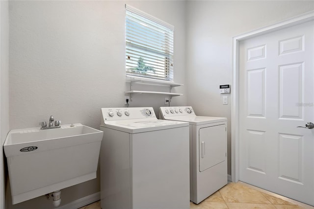 clothes washing area featuring washing machine and clothes dryer, light tile patterned flooring, and sink