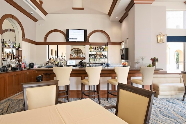 dining space featuring bar area and a high ceiling