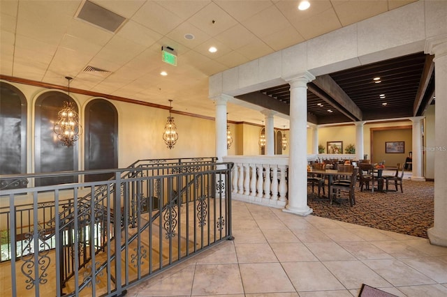 hall featuring tile patterned floors, ornamental molding, and a chandelier