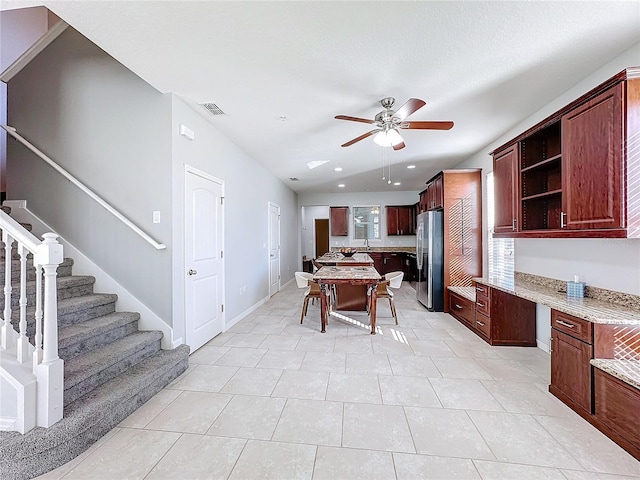 kitchen featuring stainless steel fridge, ceiling fan, light stone counters, and light tile patterned floors