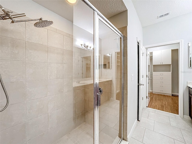 bathroom featuring tile patterned flooring, an enclosed shower, and a textured ceiling