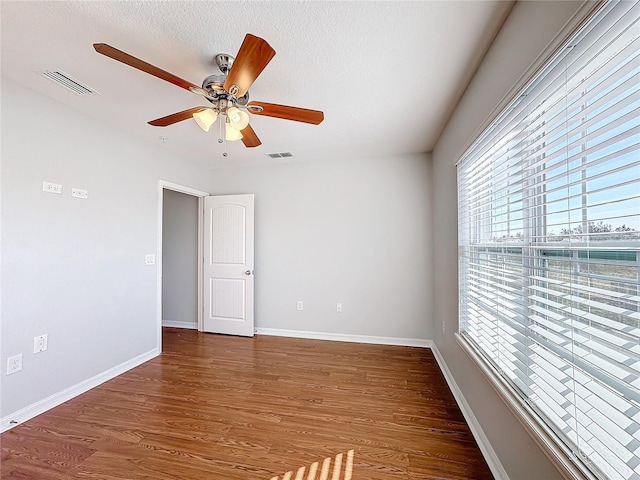 unfurnished room with ceiling fan, dark wood-type flooring, and a textured ceiling