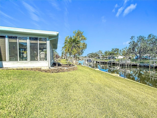 view of yard with a water view, a dock, and a sunroom