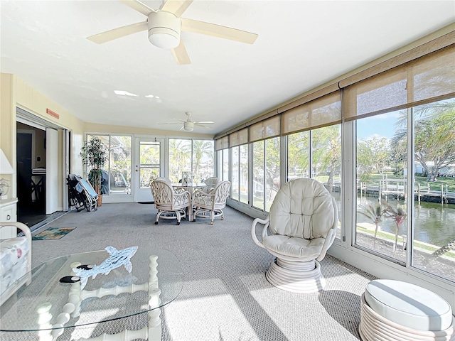 sunroom / solarium with ceiling fan, plenty of natural light, and a water view