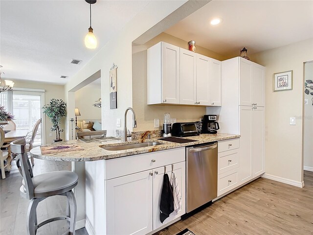 kitchen with dishwasher, sink, decorative light fixtures, light stone counters, and white cabinetry