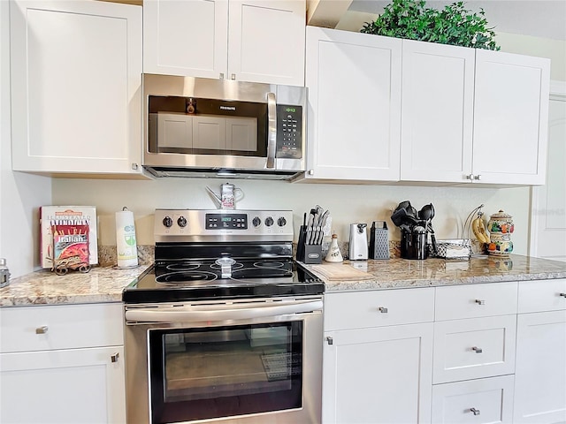 kitchen with white cabinets, light stone countertops, and appliances with stainless steel finishes