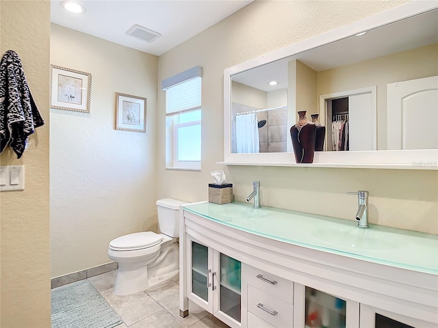 bathroom with tile patterned flooring, vanity, toilet, and walk in shower