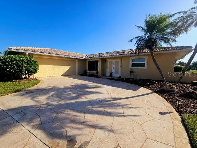 4 Windsor Dr, Englewood, FL 34223 - ranch-style home with a tiled roof, a garage, stucco siding, french doors, and driveway