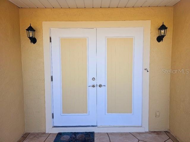 4 Windsor Dr, Englewood, FL 34223 - view of exterior entry with stucco siding and french doors