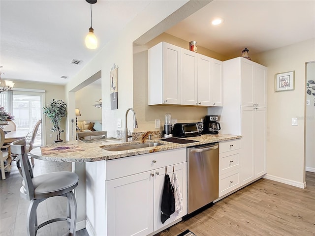 4 Windsor Dr, Englewood, FL 34223 - kitchen with a sink, light wood-style floors, a kitchen bar, stainless steel dishwasher, and light stone counters