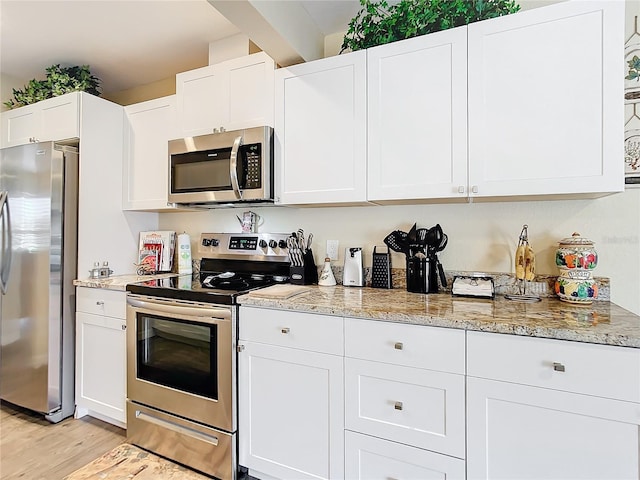 4 Windsor Dr, Englewood, FL 34223 - kitchen with stainless steel appliances, light wood-type flooring, light stone counters, and white cabinetry