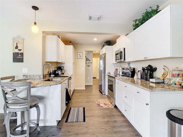 4 Windsor Dr, Englewood, FL 34223 - kitchen with visible vents, white cabinets, a sink, light wood-type flooring, and appliances with stainless steel finishes