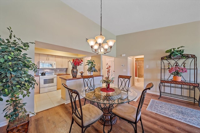 dining area with high vaulted ceiling, light hardwood / wood-style flooring, and a notable chandelier