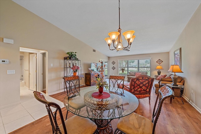 dining area with light hardwood / wood-style flooring, high vaulted ceiling, and a chandelier